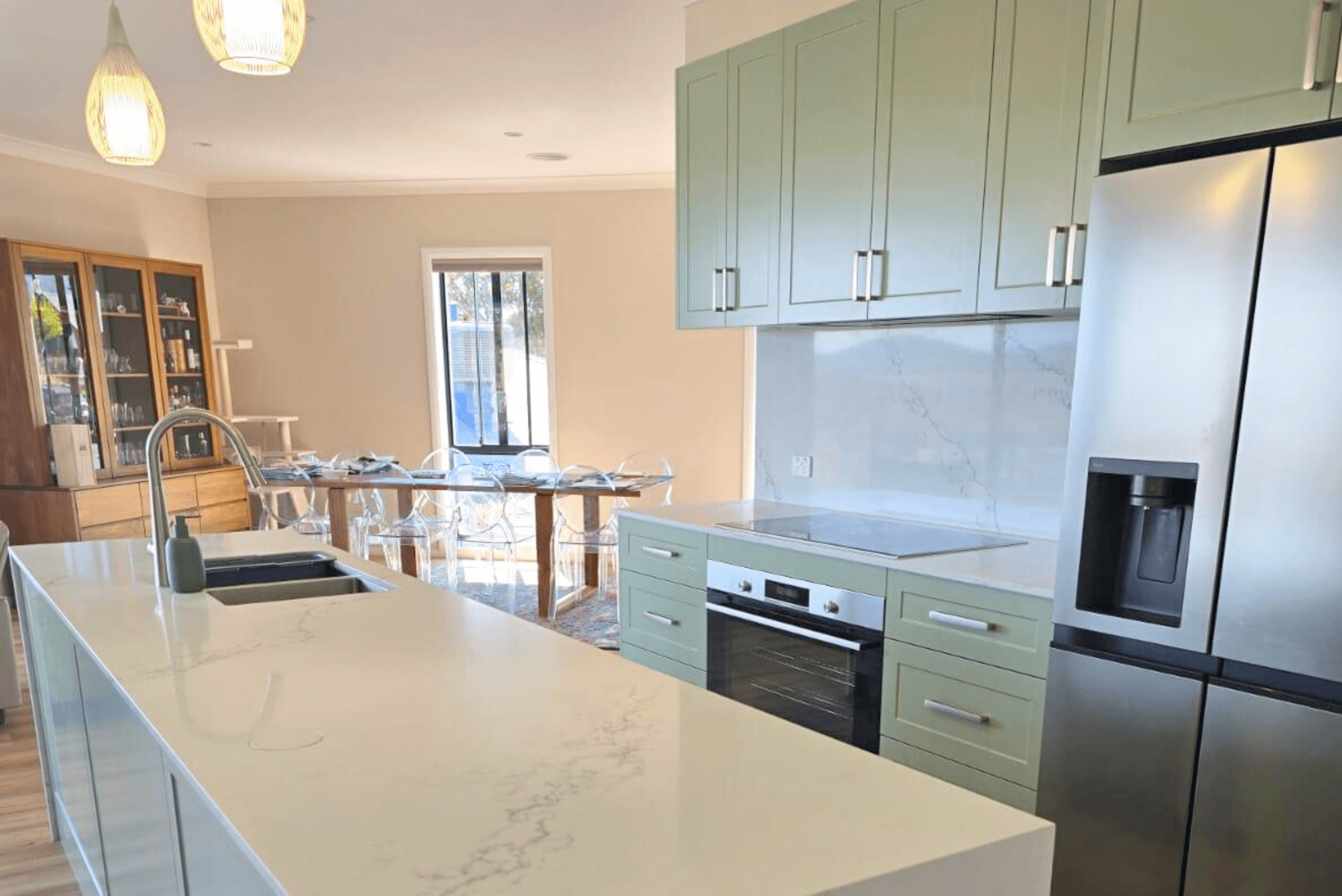 Modern kitchen renovation in Canberra, Australia with marble countertops and green cabinetry.
