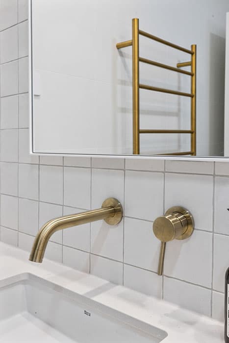 Modern bathroom renovation in Canberra with brass fixtures and white tiles
