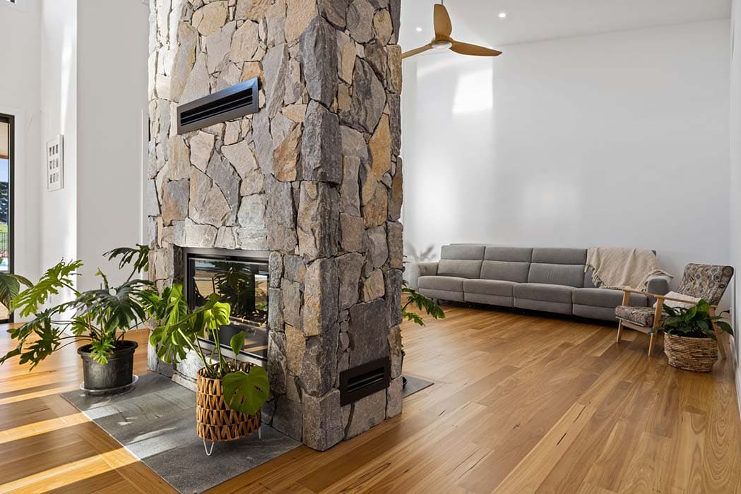 Modern living room with stone fireplace and timber flooring in Canberra, Australia