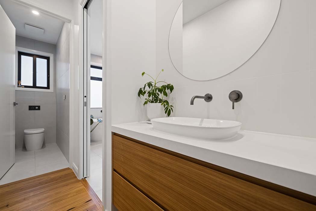 Modern bathroom renovation in Canberra, Australia with wooden vanity and sleek finishes.