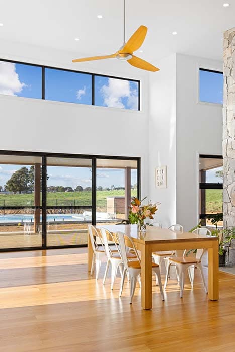Modern dining area in a new build home in Canberra, Australia with large windows and timber flooring.