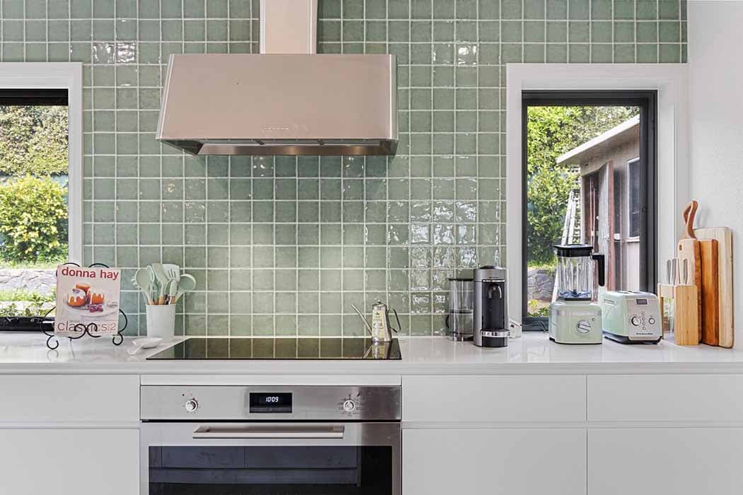 Modern kitchen renovation in Canberra with green tile backsplash and sleek appliances.