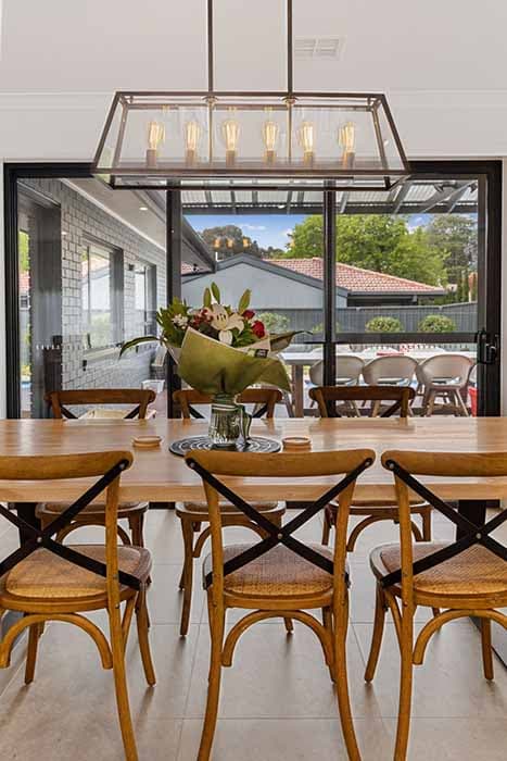 Modern dining area renovation in Canberra, Australia with stylish lighting and cross-back chairs.