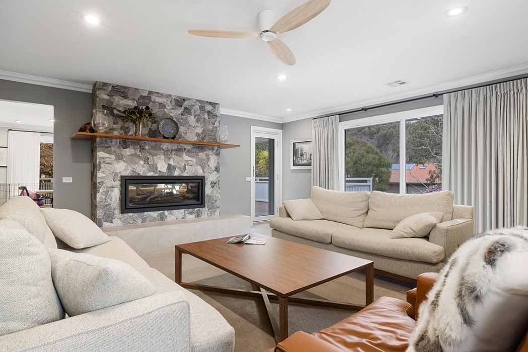 Modern living room renovation in Canberra, Australia with stone feature wall and fireplace.