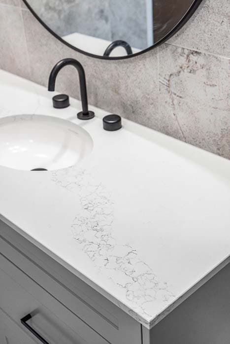 Modern bathroom renovation in Canberra with sleek white countertop and black fixtures.