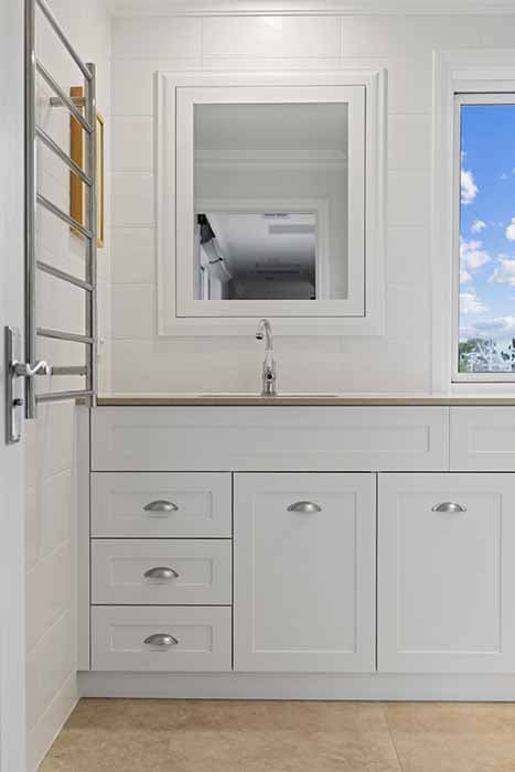 Modern bathroom renovation in Canberra, Australia with sleek white cabinetry and natural light.