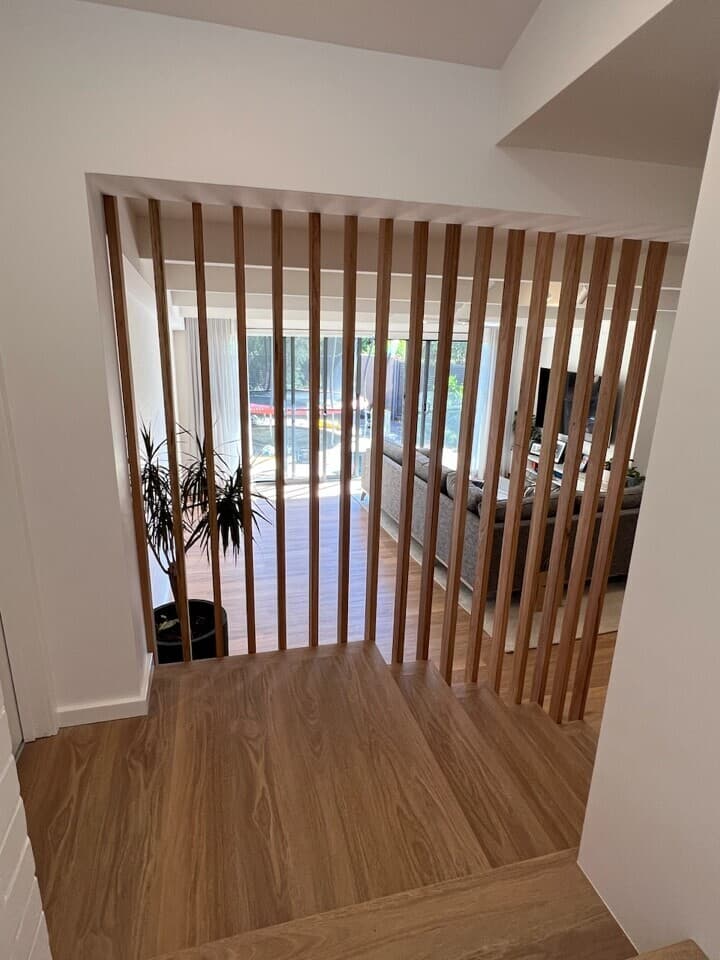 Modern entryway renovation in Canberra, showcasing wooden slat partition and warm timber flooring.
